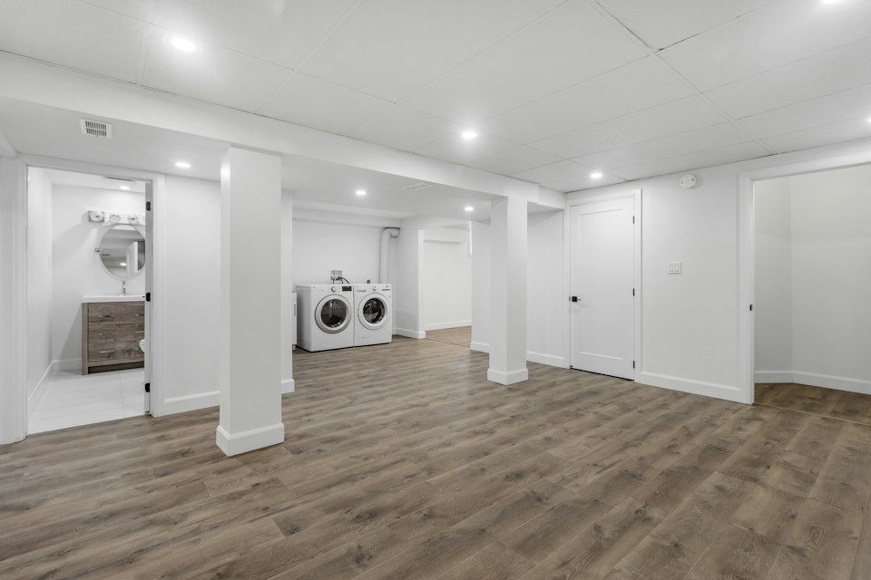 Finished basement living space with modern vinyl plank flooring and recessed lighting